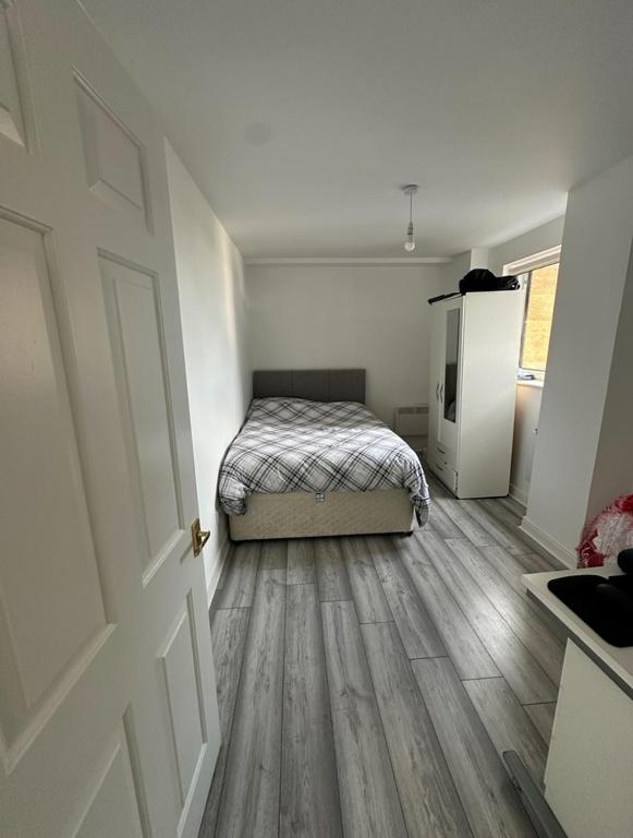 a white room with a bed and a refrigerator at Room in a Shared Flat, E16 in London