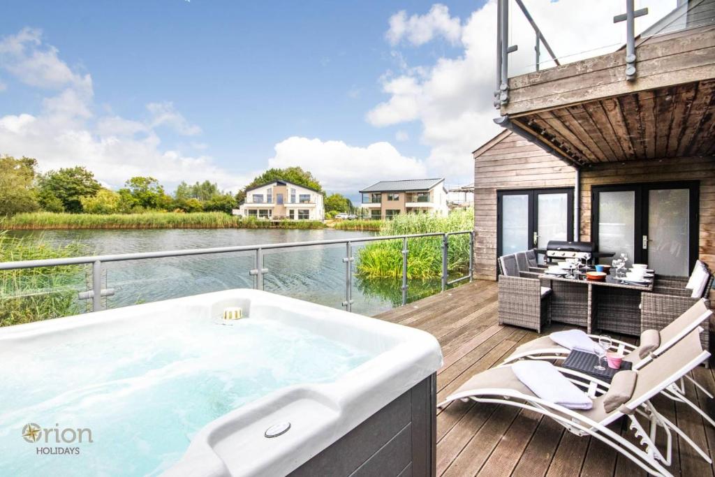 a hot tub on a deck next to the water at Waters Edge 04, Waterside Lodge P in South Cerney
