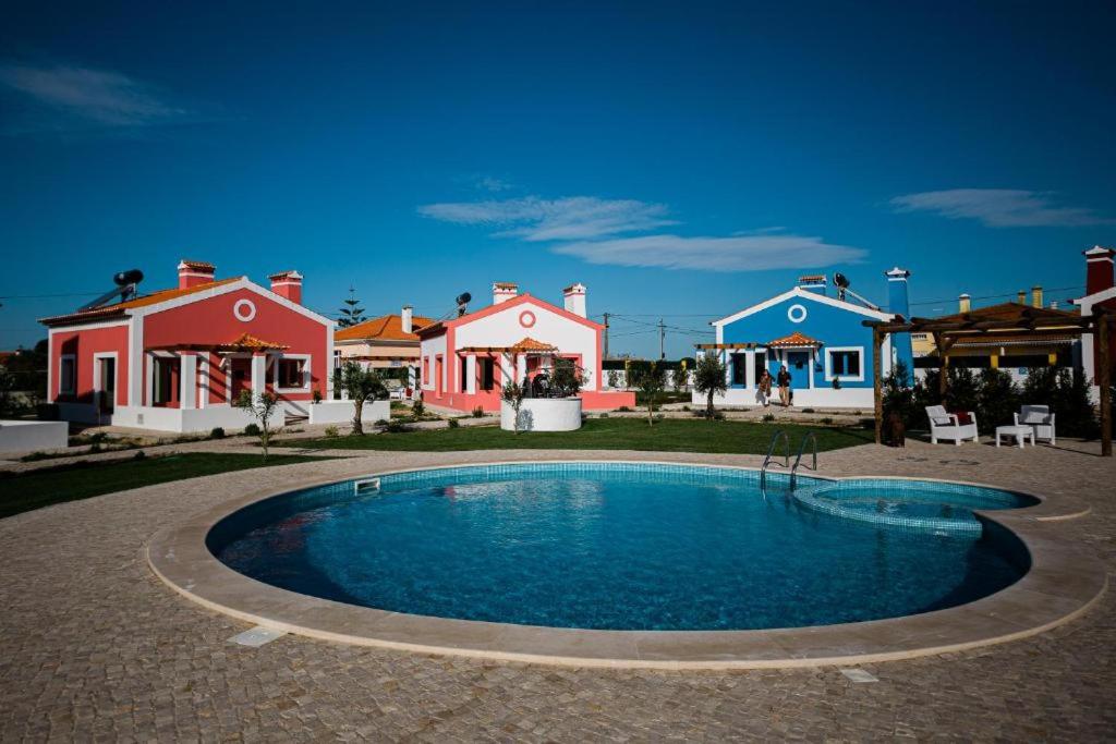 a swimming pool in front of a group of houses at QR Casas de Campo in Vale de Santarém