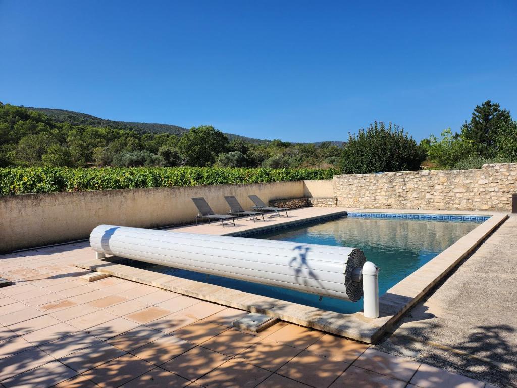 una piscina con un tubo blanco junto a una pared en gîte Les Pégots - studio en Ménerbes