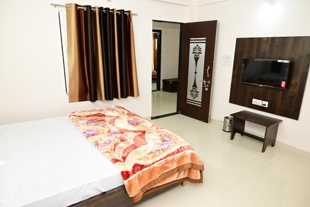 ein Schlafzimmer mit einem Bett und einem TV in einem Zimmer in der Unterkunft Hotel Shree chandram - 10min walking distance to श्रीNathji temple in Nāthdwāra