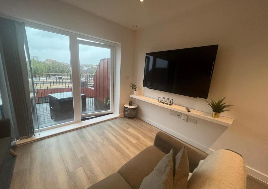 a living room with a couch and a flat screen tv at Private room in London with balcony in Woolwich