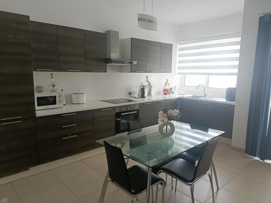 a kitchen with a glass table and black chairs at 54 RW Ashley in Naxxar