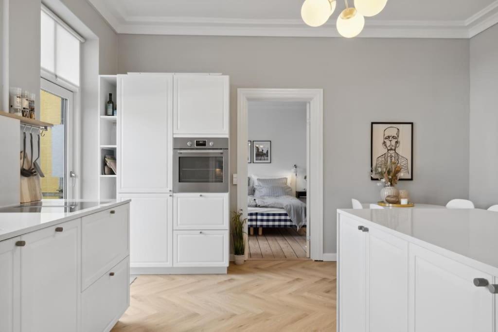 cocina blanca con armarios blancos y sala de estar. en City center apartment w/ large private balcony, en Aalborg