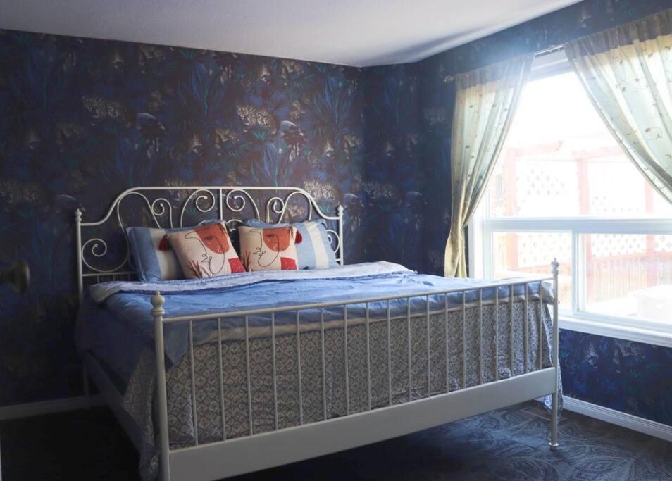 een slaapkamer met een bed met een blauwe muur bij A comfortable and fun place, perfect location! in London