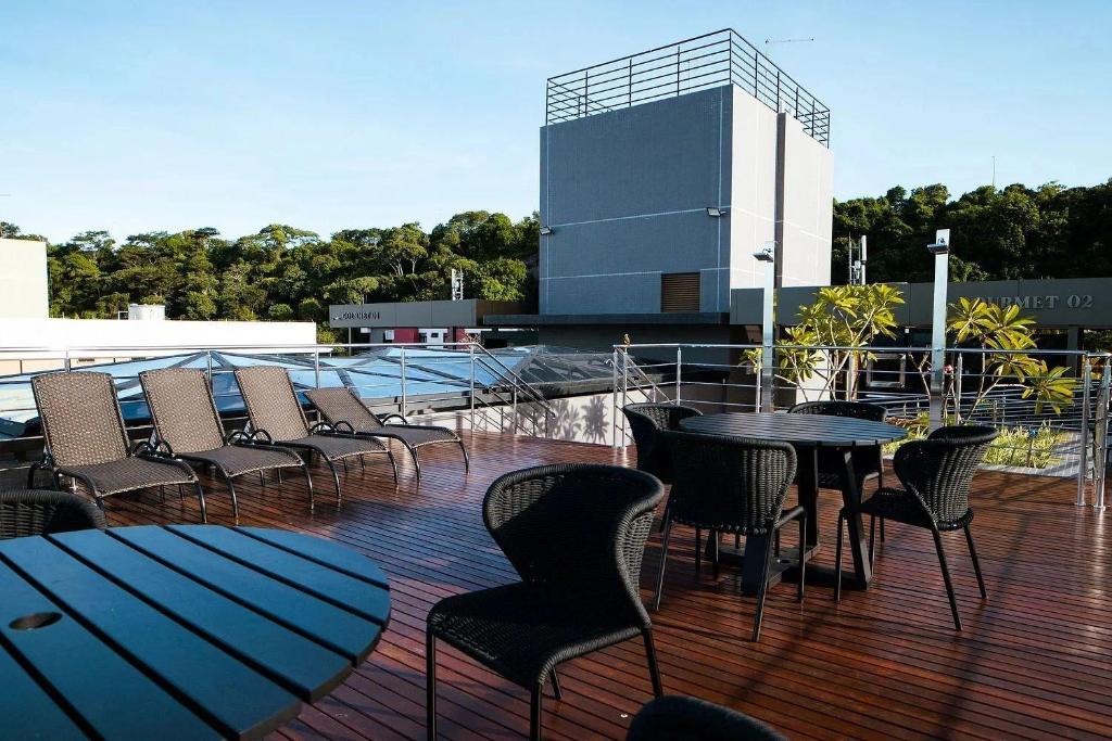 eine Terrasse mit Stühlen und Tischen sowie ein Gebäude in der Unterkunft Unity - Cabo Branco in João Pessoa