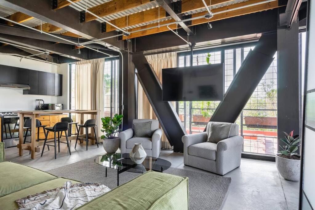 uma sala de estar com um sofá e cadeiras e uma televisão em Buenos Aires LOFT by Pardela, Colonia Americana em Guadalajara