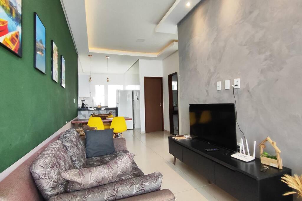 a living room with a couch and a flat screen tv at Casa aconchegante, 1 suit e 2 quartos/escritório. in Petrolina