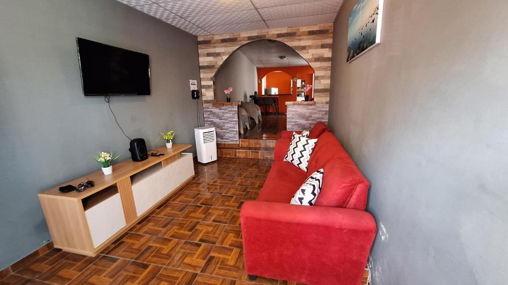 Yanira's house في سانتا آنا: غرفة معيشة بها أريكة حمراء وتلفزيون