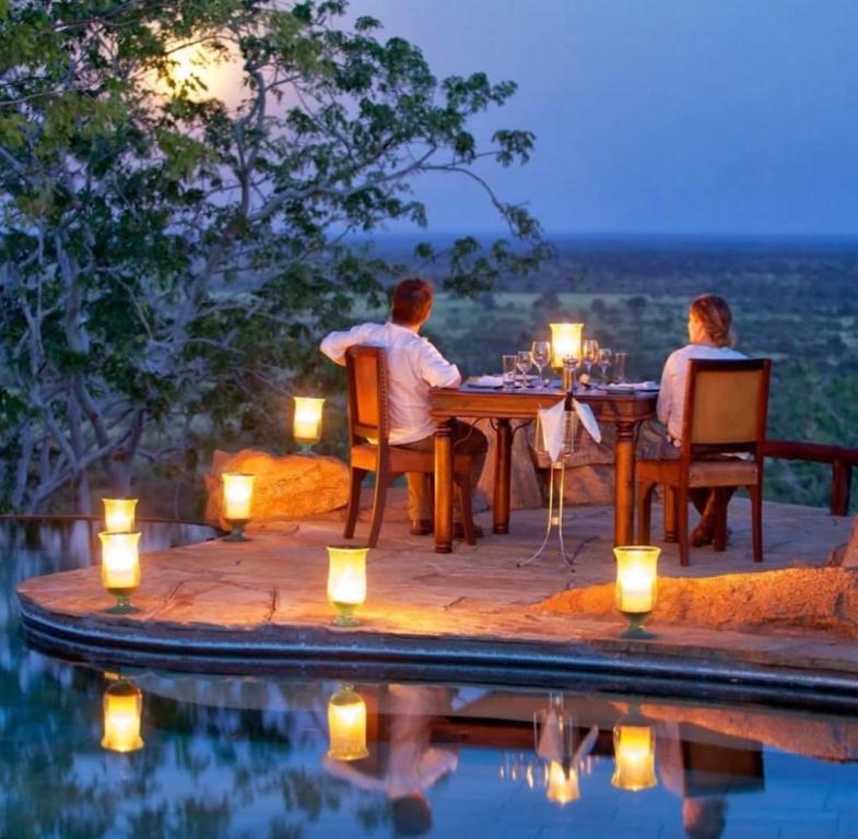 a man and woman sitting at a table by a pool at Wildlife Enthusiasts in Sekenani