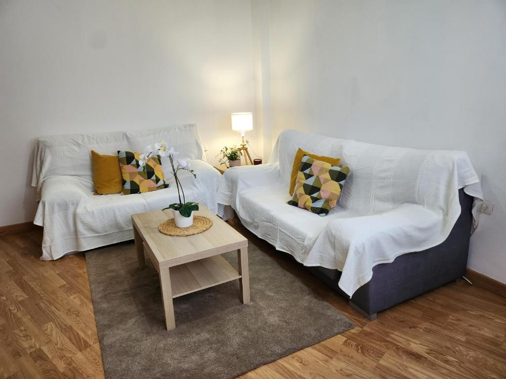 Una sala de estar con dos sofás blancos y una mesa. en CASA GARA ISABEL, en Arrecife