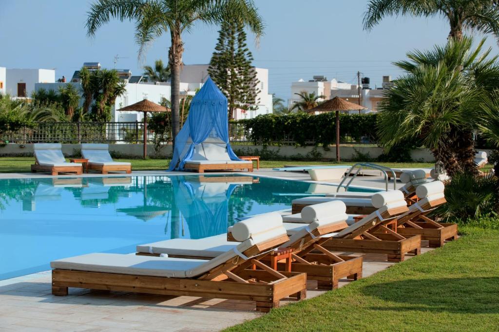 Socrates Hotel Malia Beach في ماليا: مسبح وكراسي صالة جلوس ومنتجع