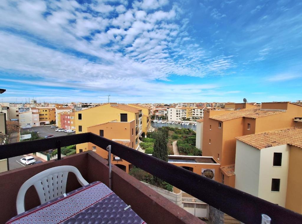 un balcon avec une table et une vue sur une ville dans l'établissement Cap d'Agde - Studio lumineux 2 - 4 personnes Terrasse avec vue, au Cap d'Agde