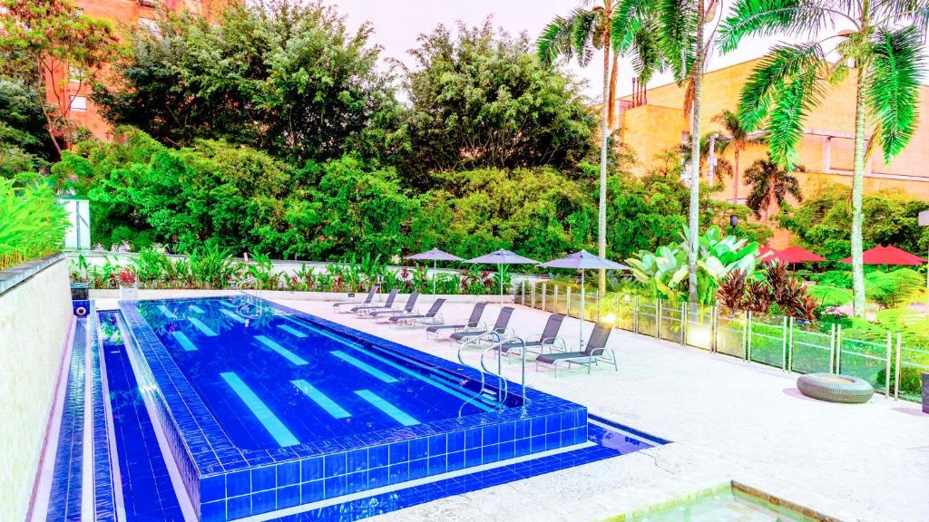 einen Pool mit Stühlen und Sonnenschirmen in einem Resort in der Unterkunft NH Collection Medellin Royal in Medellín