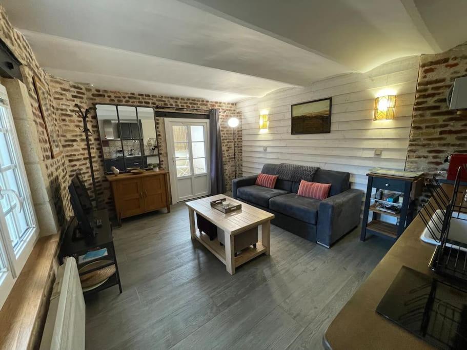 ein Wohnzimmer mit einem Sofa und einem Tisch in der Unterkunft Le paddock deauvillais in Deauville