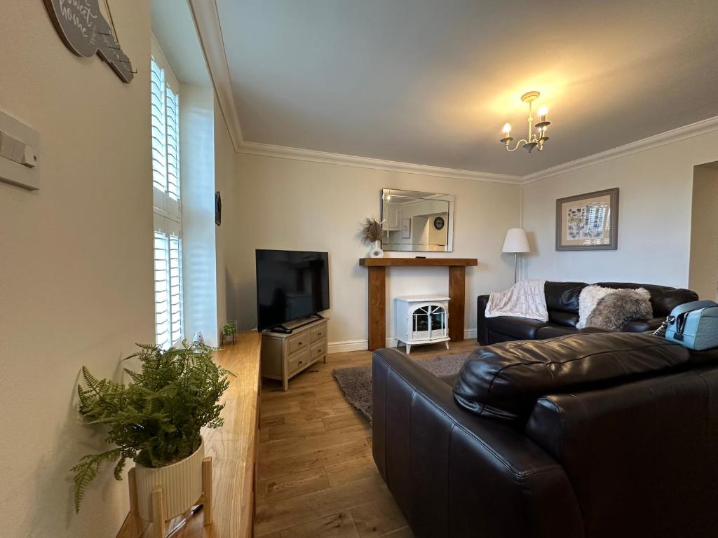 a living room with a leather couch and a television at The Cosy Cottage Retreat! Perfect for Contractors, Relocators, Getaway in Llantrisant