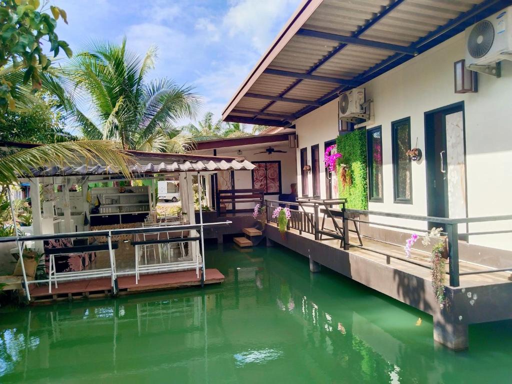 a house on a river with green water at Maidok Homestay(ไม้ดอกโฮมสเตย์) in Ban Pak Ba Ra