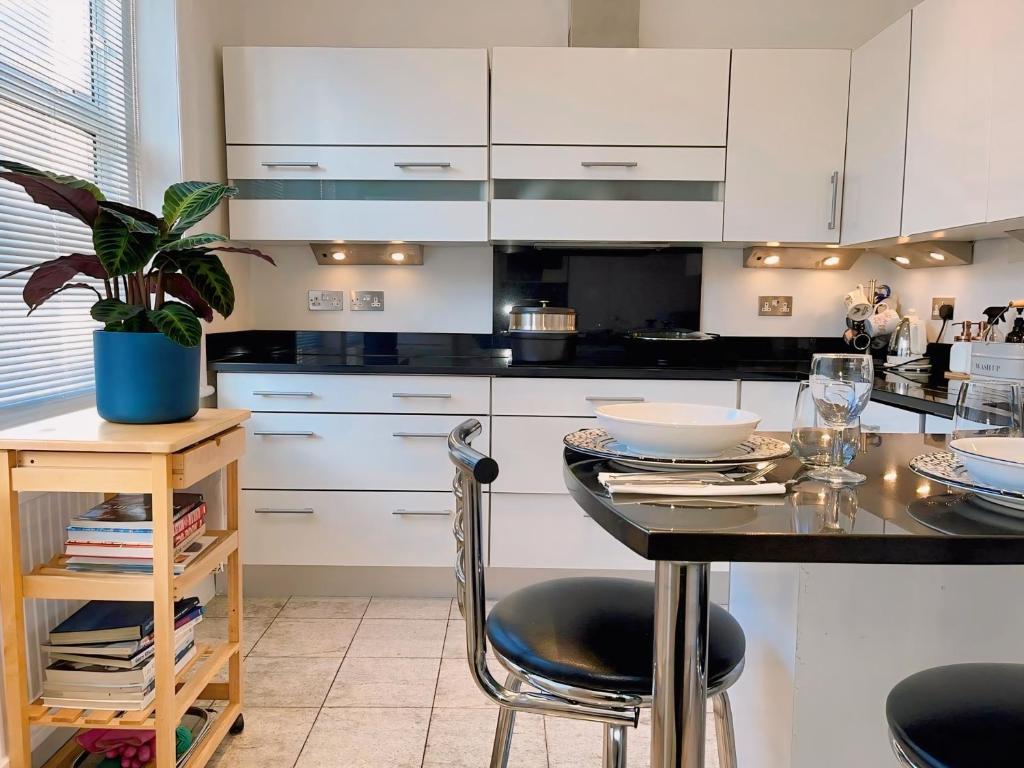 a kitchen with white cabinets and a table with a potted plant at Spacious Belsize Park apartment close to station in London