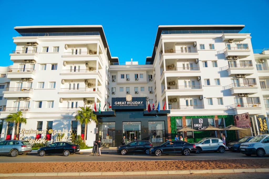 un grande edificio bianco con macchine parcheggiate di fronte di Great Holiday Apart-Hotel & Penthouse ad Agadir