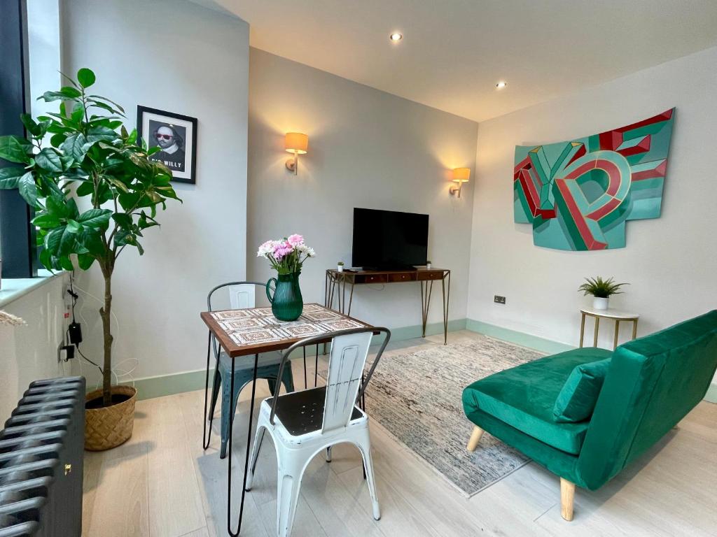 a living room with a table and a green chair at Cute 1-Bedroom Ground Apartment in Stoke Newington in London