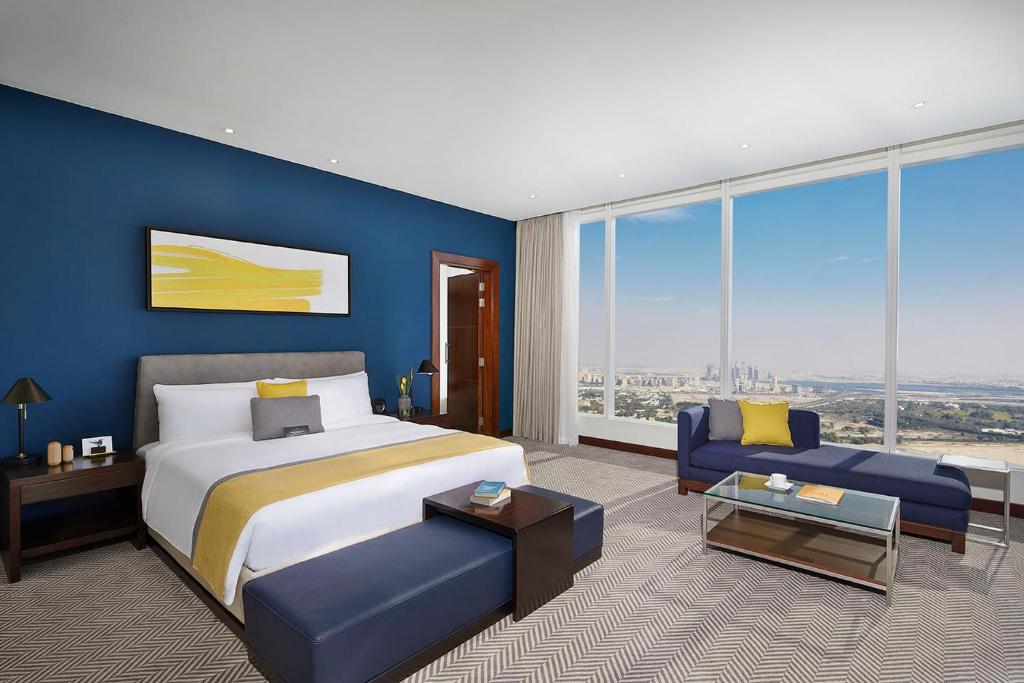 voco Dubai, an IHG Hotel في دبي: غرفة نوم بسرير كبير وجدار ازرق
