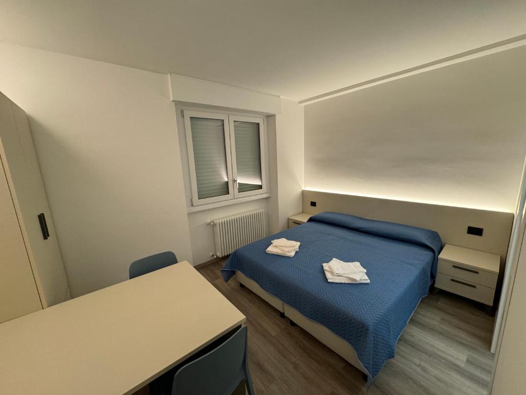 um pequeno quarto com uma cama azul e uma mesa em Giagi B&B em Trento