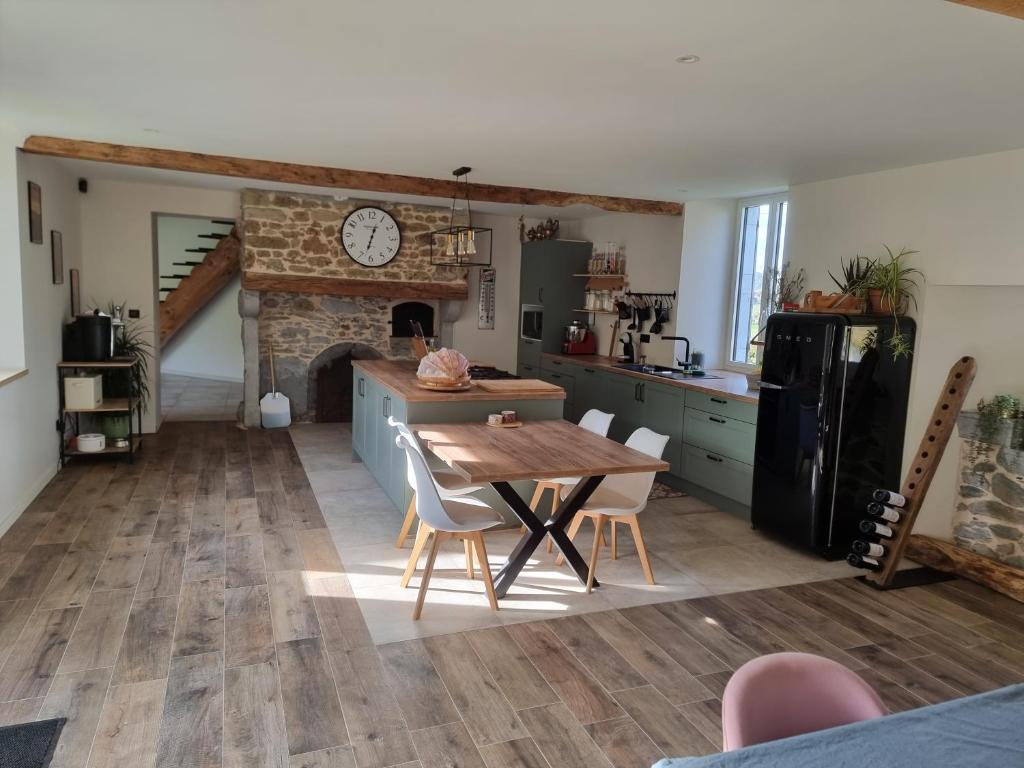 a kitchen and dining room with a table and a fireplace at Charmant corps de ferme à la montagne. in Montsérié