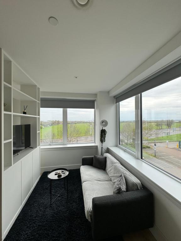 a living room with a couch and two large windows at LUXX Apartment & Suites, London Heathrow Airport, Terminal 4, Piccadilly underground Train station nearby! in New Bedfont