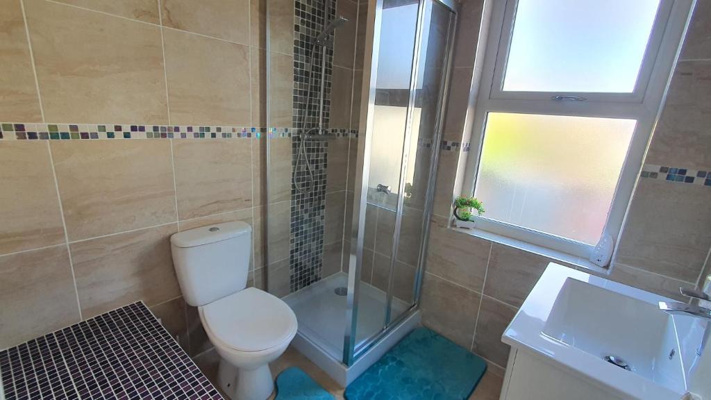 uma casa de banho com um WC, um chuveiro e uma janela. em Highfield House! em Wellingborough