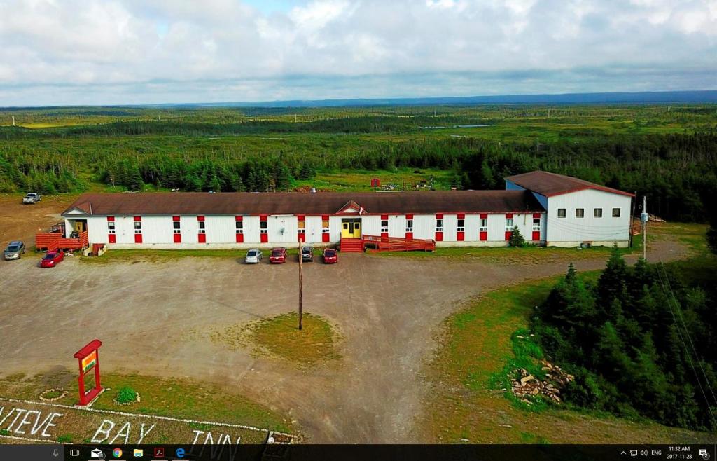 an aerial view of a large white barn with a parking lot at Genevieve Bay Inn in River of Ponds