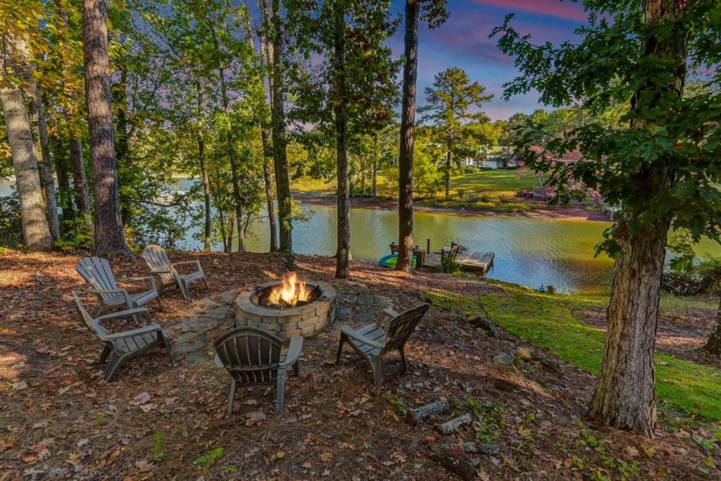 a fire pit with chairs next to a lake at Hilton Lake Home - Hot Tub in Hollywood Point