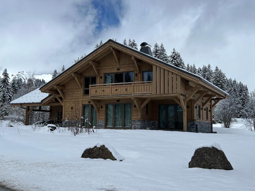 uma casa de madeira na neve com duas pedras na neve em Chalet Clémence em Taninges