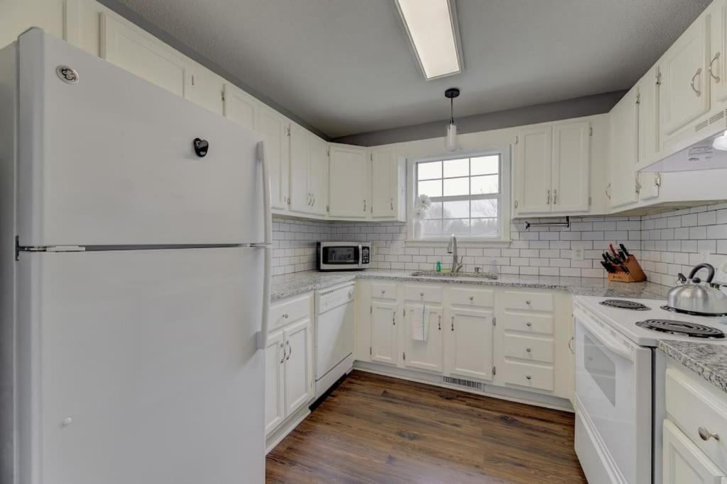 a white kitchen with white cabinets and a refrigerator at Lexington Home Near Main St in Lexington