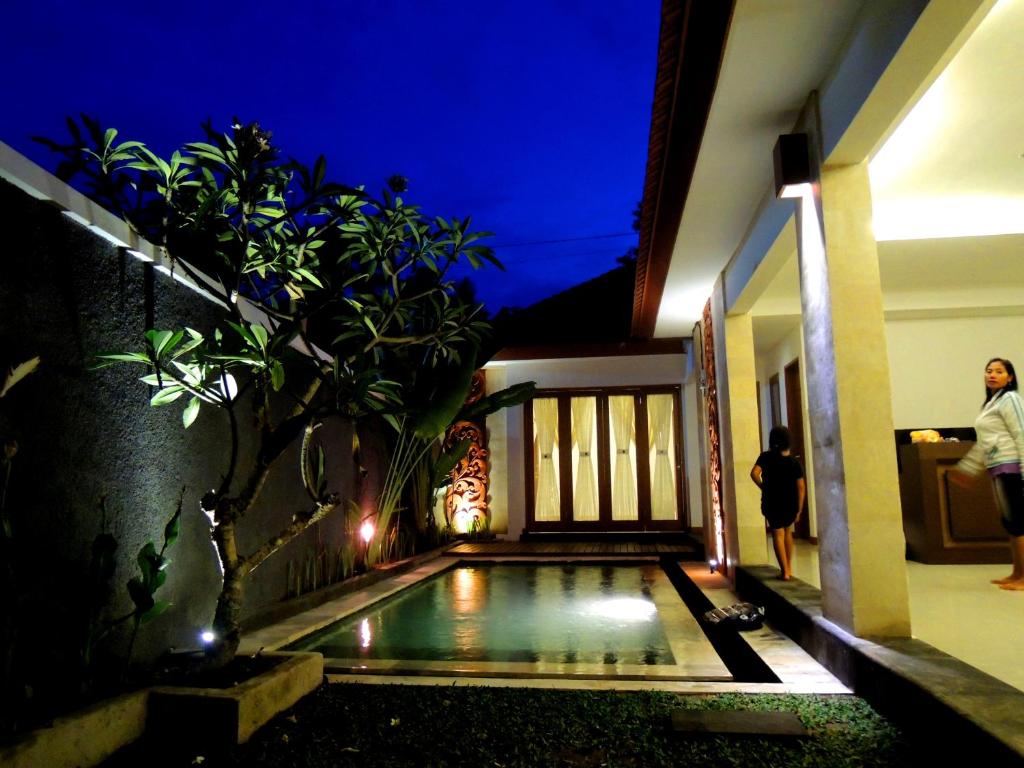 a house with a swimming pool at night at Jayastuti House in Ubud