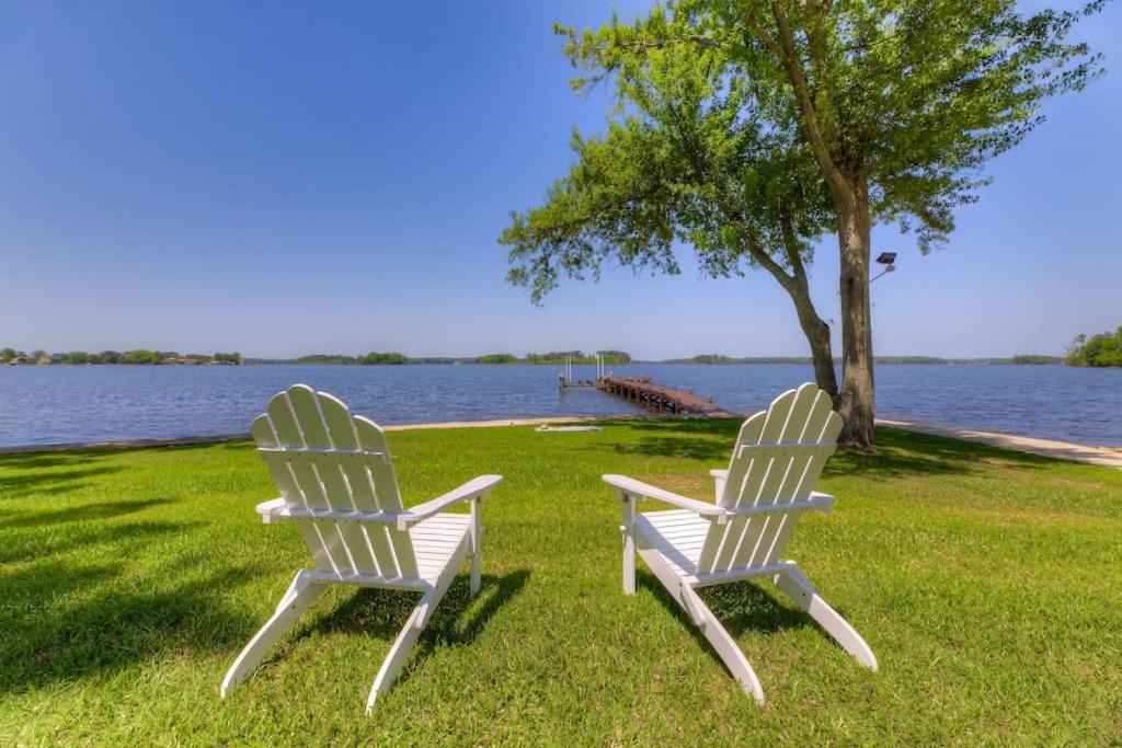 two white chairs sitting in the grass by the water at Modern Villa - Lake Views in Lake Murray Shores