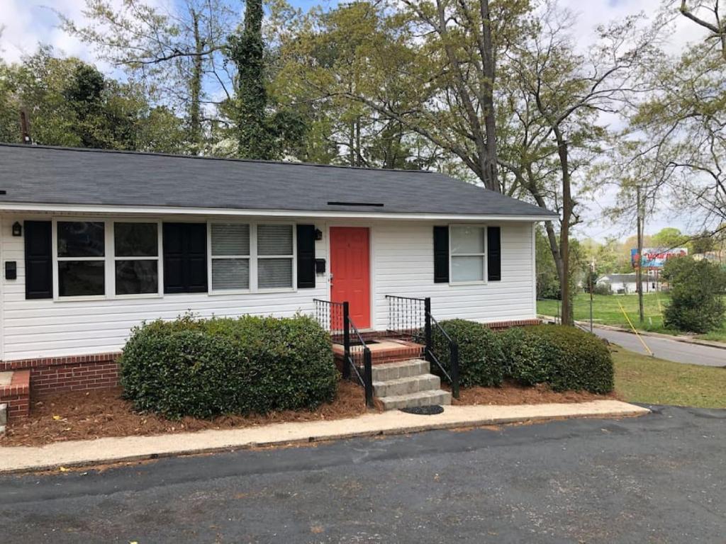 a white house with a red door on a street at Modern Renovated Apartment in Columbia