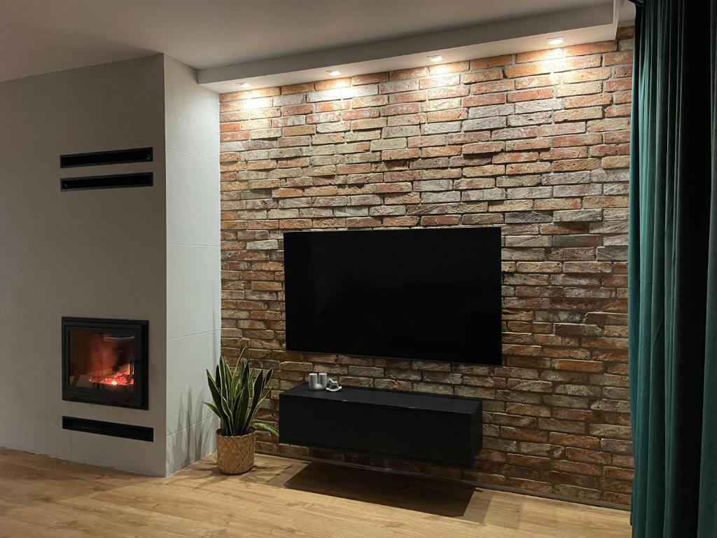 a television on a brick wall with a fireplace at MARS HOME in Kołobrzeg