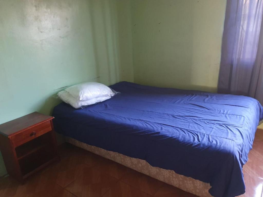 um pequeno quarto com uma cama azul e uma mesa de cabeceira em Acogedora Habitación San Pedro de Atacama em Toconao