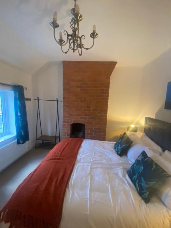 a bedroom with a large bed and a chandelier at THE ENCHANTED COTTAGE in Rolleston
