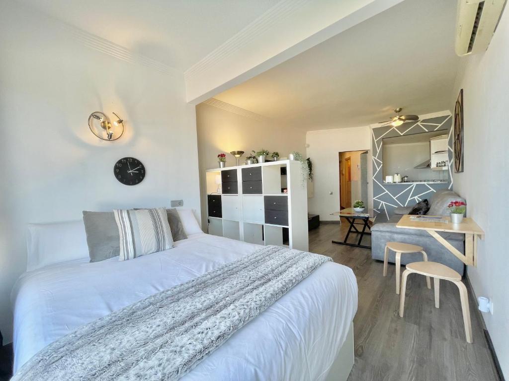 Schlafzimmer mit einem weißen Bett und einem Schreibtisch in der Unterkunft La Colina - Moderno y acogedor estudio vista mar in Torremolinos