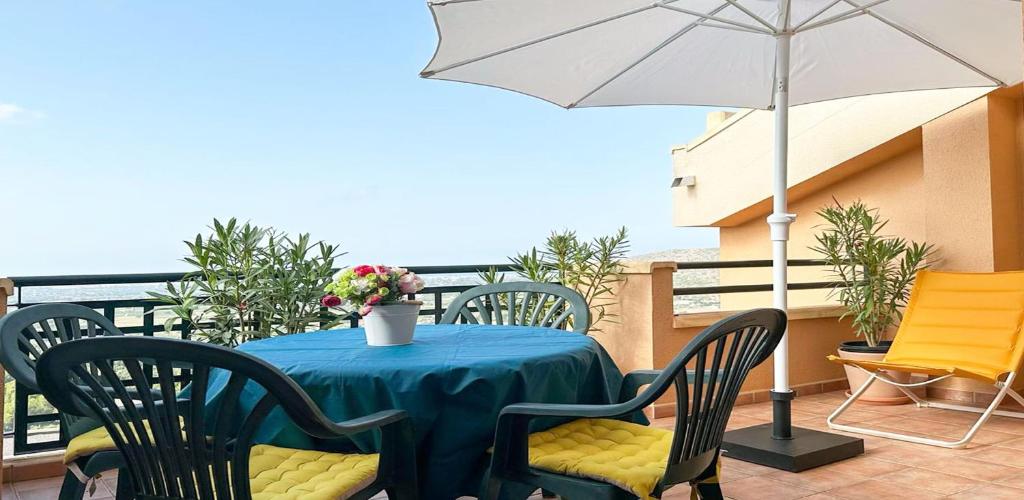 a table with chairs and an umbrella on a balcony at Cosy home / vue mer / vue montagne / 4 voyageurs in Muntanya la Sella