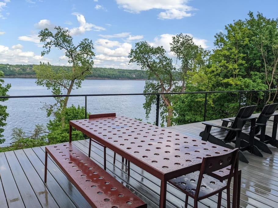 a table and chairs on a deck with a view of a lake at Hudson River Cliff House in Saugerties