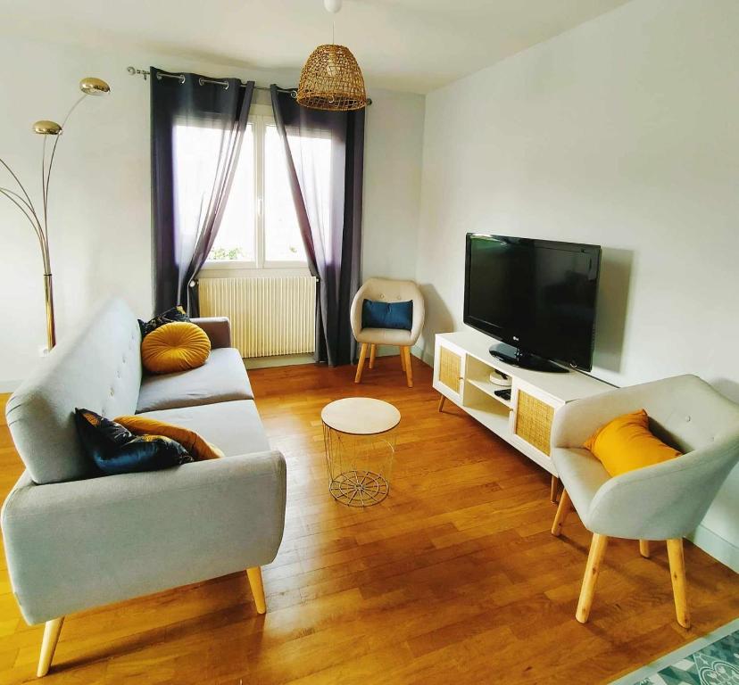 a living room with a couch and a tv at L'étape Nuitonne - Gîte avec jardin pour 6 personnes in Nuits-Saint-Georges