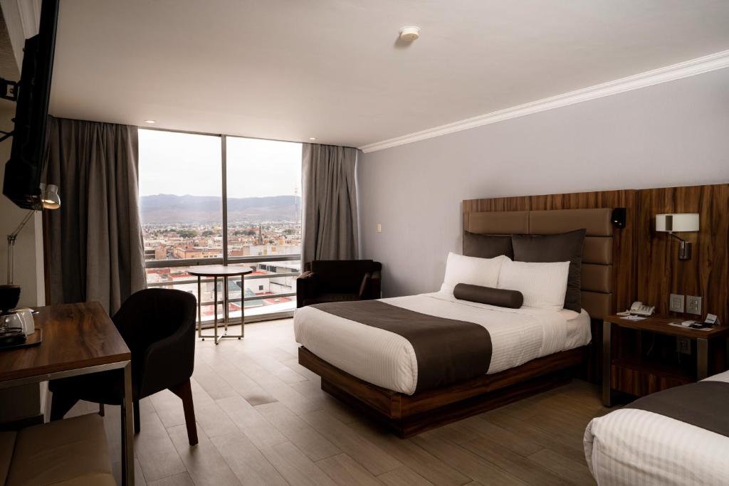 サン・ルイス・ポトシにあるPanoramaのベッドとデスクが備わるホテルルームです。