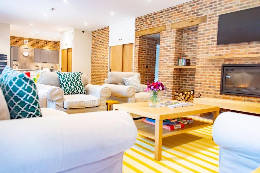 a living room with white furniture and a brick wall at The Kennels in Hexham