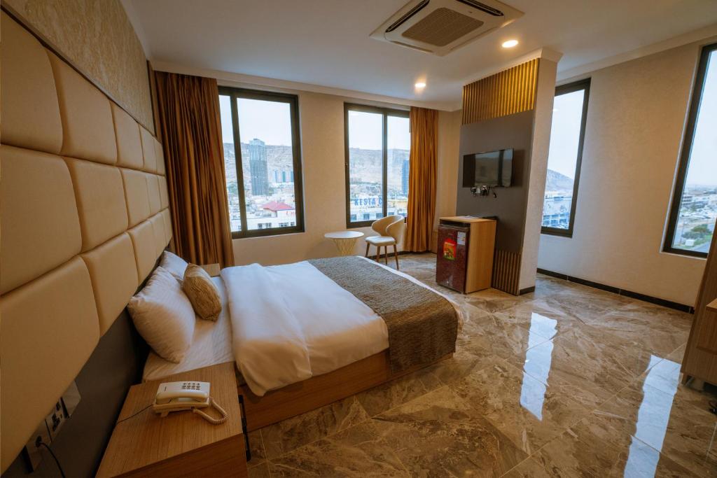 um quarto de hotel com uma cama e algumas janelas em Sarok Hotel em Dohuk