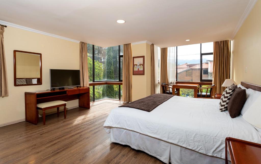 a bedroom with a bed and a desk with a television at Hotel NASS Pinar del Lago in Cuenca