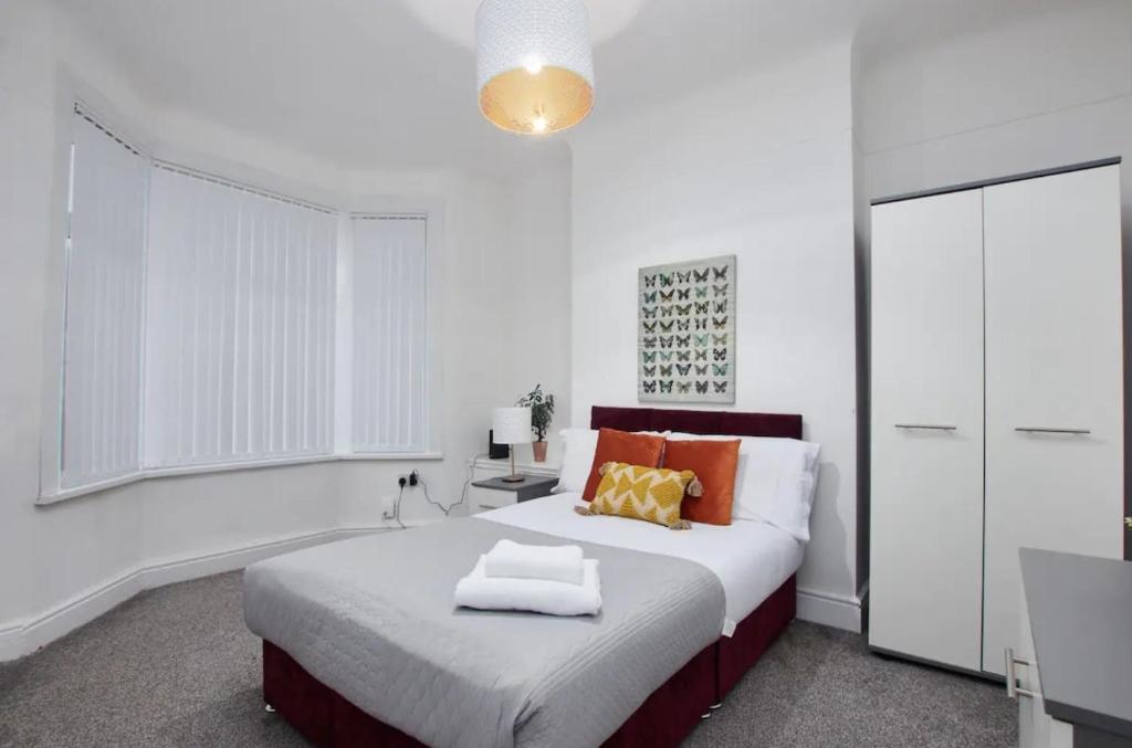 1 dormitorio blanco con 1 cama grande con almohadas de color naranja en Spacious 4 bedroom house in Wallasey for 7 people with parking BridgeCity, en Wallasey