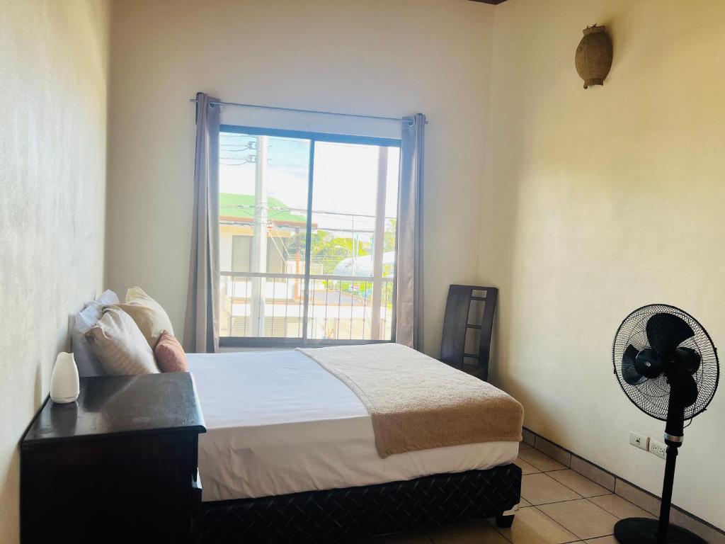 um quarto com uma cama, uma janela e uma ventoinha em Naty’s Apartamento em La Cruz
