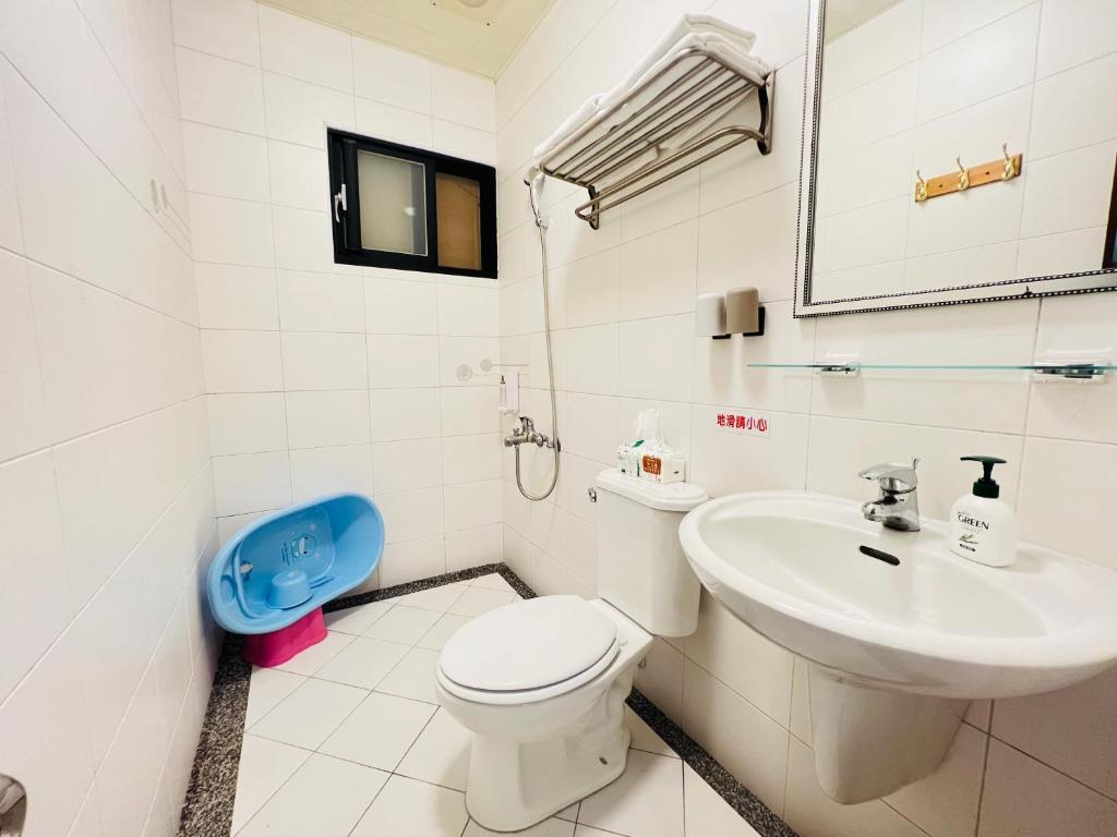 a white bathroom with a toilet and a sink at 享樂時光親子民宿 in Tainan
